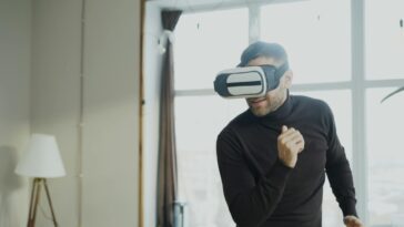 Adult male experiencing virtual reality with a headset inside a modern room.