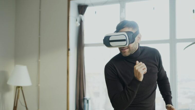Adult male experiencing virtual reality with a headset inside a modern room.