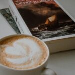 Elegant close-up of latte art and a book, creating a cozy reading atmosphere indoors.