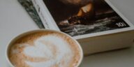 Elegant close-up of latte art and a book, creating a cozy reading atmosphere indoors.