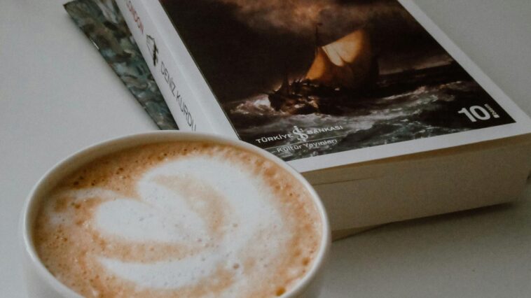 Elegant close-up of latte art and a book, creating a cozy reading atmosphere indoors.