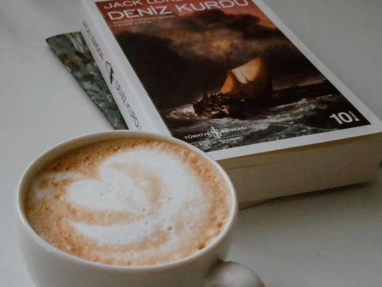 Elegant close-up of latte art and a book, creating a cozy reading atmosphere indoors.