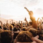 Energetic crowd enjoying live music at a festival during sunset.