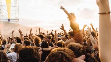 Energetic crowd enjoying live music at a festival during sunset.