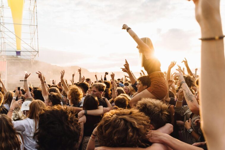 Energetic crowd enjoying live music at a festival during sunset.