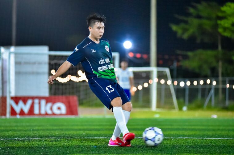 Soccer player in action on a lit field, capturing the dynamic energy of the game at night in Hà Nội.