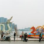 People preparing for Lunar New Year 2026 by a dragon statue along a lakeside.