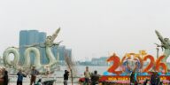 People preparing for Lunar New Year 2026 by a dragon statue along a lakeside.
