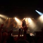 A dynamic live rock band performance with vibrant stage lights and an enthusiastic audience.