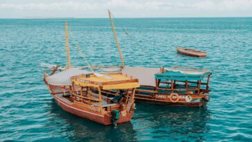 Enjoy the serene view of traditional dhows sailing in the turquoise Zanzibar sea.
